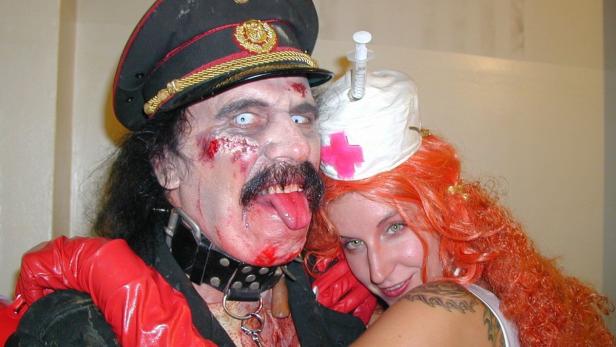 Ein Mann im Zombie-Kostüm mit roter Zunge und eine Frau im Krankenschwester-Kostüm posieren für ein Foto.