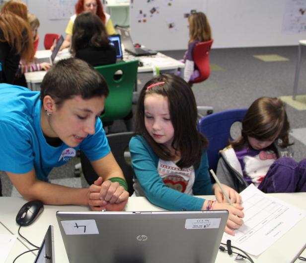 Ein Mädchen wird von einer Betreuerin bei einer Aufgabe am Laptop unterstützt.