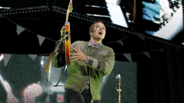 Ein Mann mit Gitarre singt auf einer Bühne.