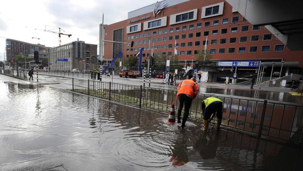 Überschwemmung vor dem VU medizinischen Zentrum in Amsterdam, während Arbeiter versuchen, das Wasser abzuleiten.