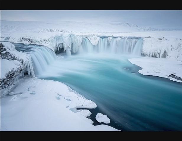 Ein Wasserfall in einer verschneiten Winterlandschaft mit Eis und Schnee bedeckt.