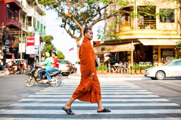 Ein buddhistischer Mönch überquert eine Straße in einer Stadt.