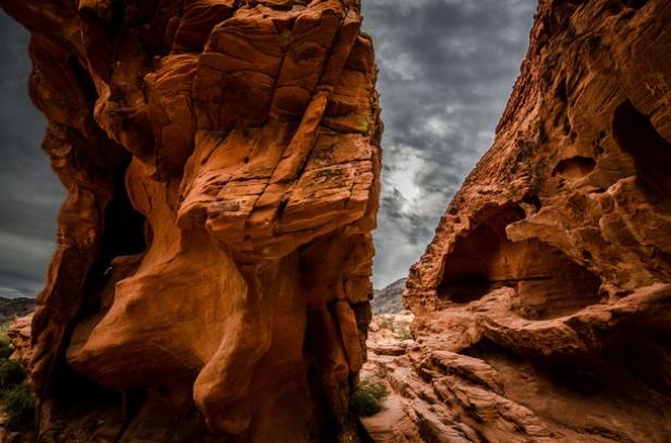 Rote Felsen bilden eine Schlucht unter einem bewölkten Himmel.