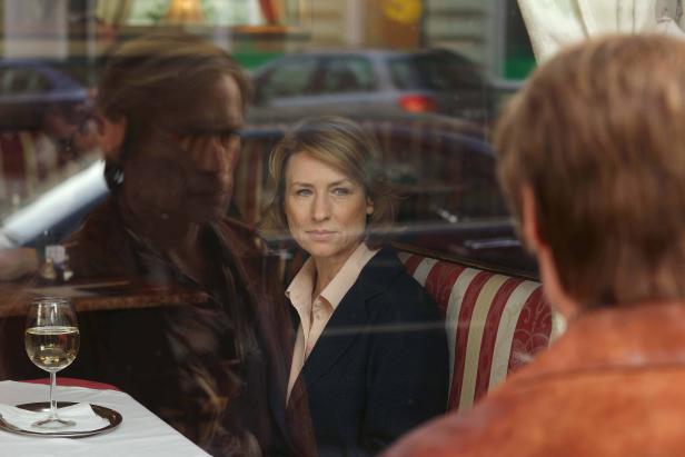 Eine Frau sitzt in einem Restaurant und blickt durch das Fenster.