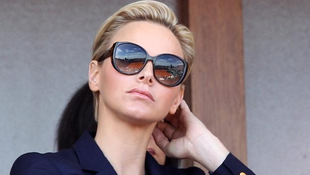 Fürstin Charlène von Monaco mit Sonnenbrille, in der sich ein Tennisplatz spiegelt.