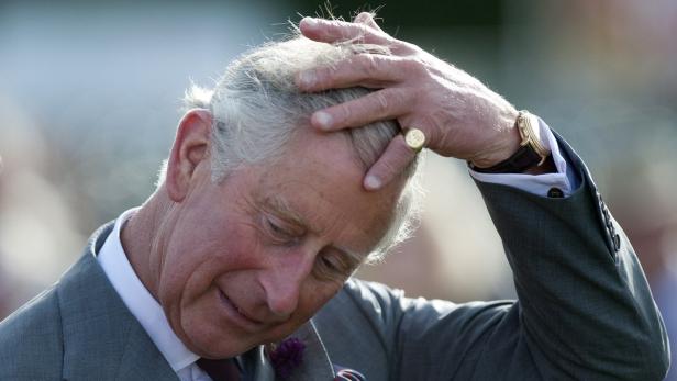König Charles III. mit der Hand auf dem Kopf.
