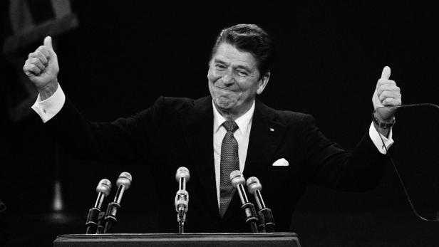 Ronald Reagan steht am Rednerpult und zeigt mit beiden Daumen nach oben.