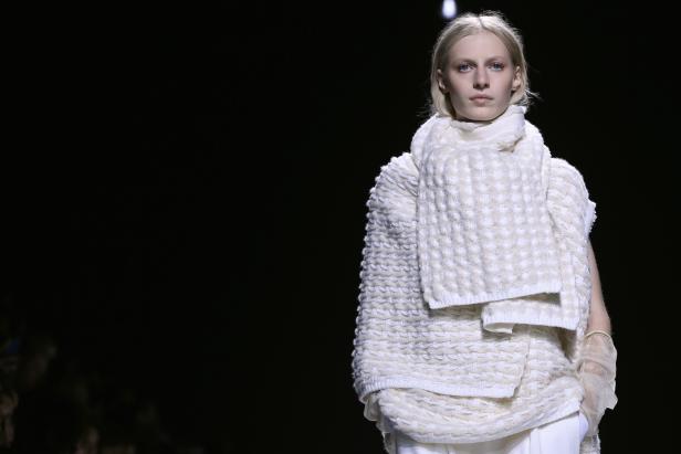 Eine Frau mit blonden Haaren trägt ein weißes Strickensemble.