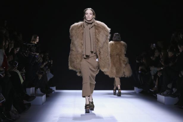 Eine Frau in einem braunen Pelzmantel und passendem Outfit auf einem Laufsteg.