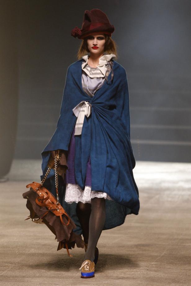 Eine Frau in einem blauen Mantel und einem roten Hut läuft auf einem Laufsteg.