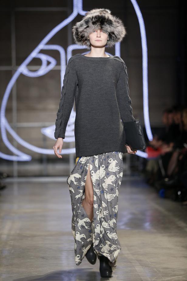 Ein Model mit Pelzmütze präsentiert ein graues Kleid und einen Rock mit Vogelmuster.