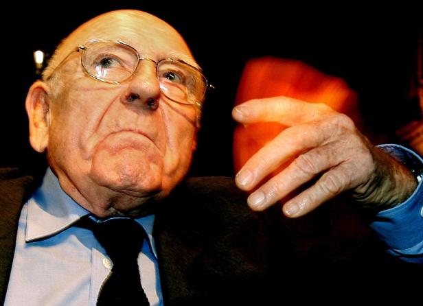 Ein älterer Mann mit Brille und Anzug blickt nach links.