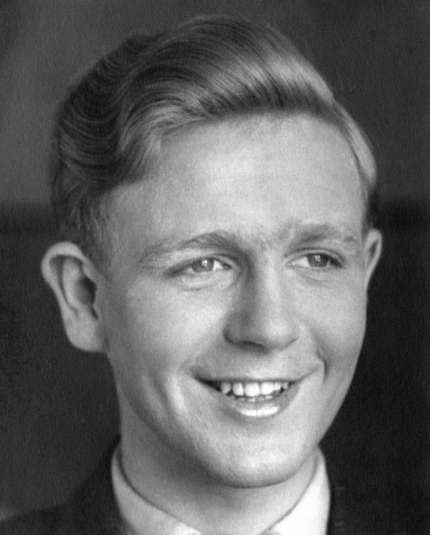 Ein junger Mann mit hellem Haar lächelt in die Kamera.