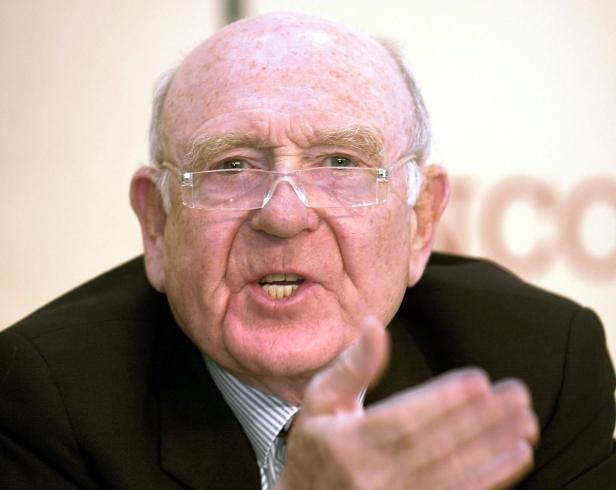 Ein älterer Mann mit Brille gestikuliert und spricht.