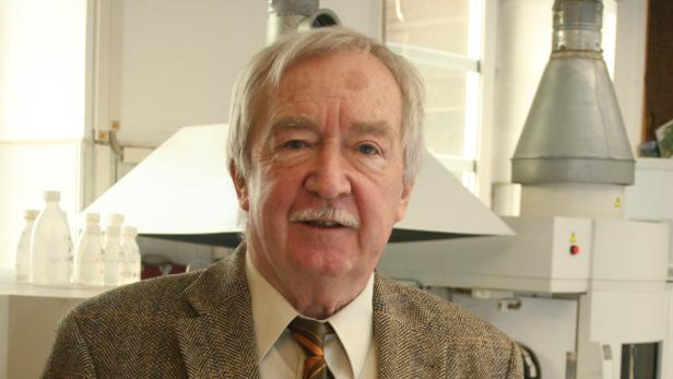 Ein älterer Mann mit grauem Haar und Schnurrbart trägt ein Tweed-Jackett.