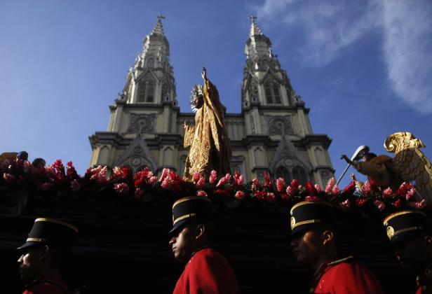 Eine Prozession mit einer Jesusstatue vor einer Kirche mit zwei Türmen.