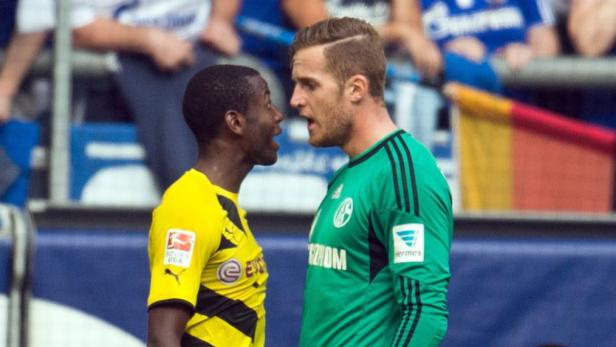 Zwei Fußballspieler von Borussia Dortmund und Schalke 04 stehen sich gegenüber und diskutieren.