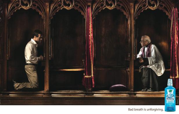 Ein Mann beichtet einem Priester in einem hölzernen Beichtstuhl.