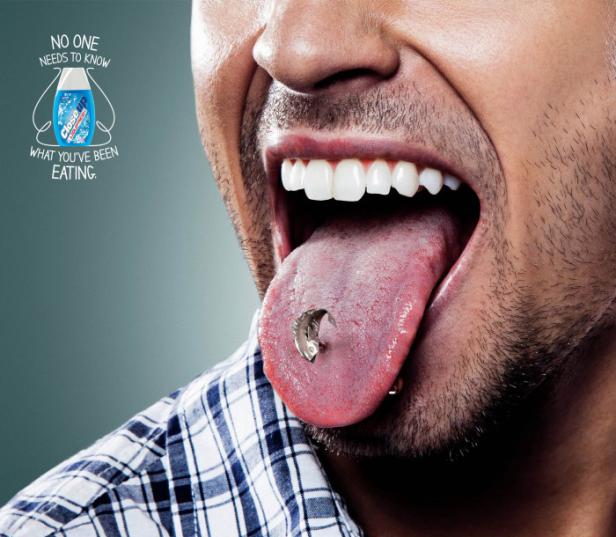 Ein Mann mit offenem Mund und einem Fisch-Zungenpiercing.