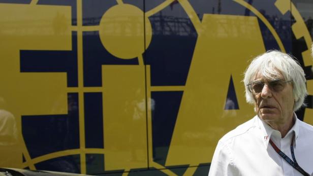 Bernie Ecclestone vor einem Bus mit dem FIA-Logo.