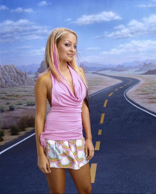 Nicole Richie posiert vor einer gemalten Kulisse mit einer Straße und Bergen.