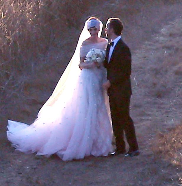 Ein Brautpaar steht in einem Feld, die Braut hält einen Blumenstrauß.