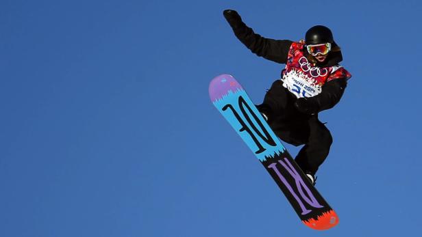 Ein Snowboarder springt vor blauem Himmel in der Luft.