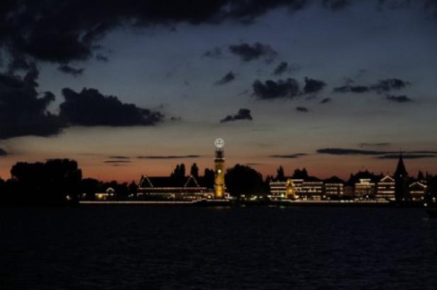 Die Skyline einer Stadt erstrahlt im Abendlicht am Wasser.