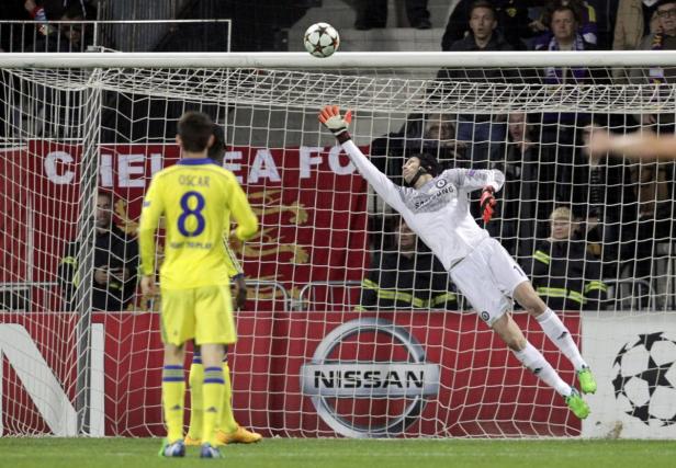 Ein Torwart springt, um einen Fußball zu halten, während ein anderer Spieler zusieht.