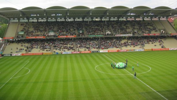 Blick auf ein Fußballstadion mit Zuschauern auf den Tribünen.