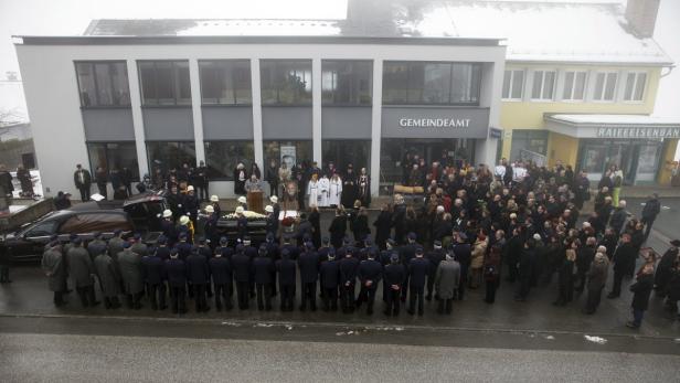 Eine Trauergemeinde versammelt sich vor dem Gemeindeamt und der Raiffeisenbank.