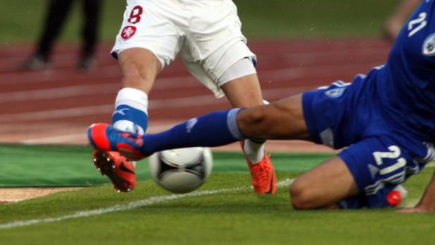 Zwei Fußballspieler kämpfen um den Ball auf dem Spielfeld.