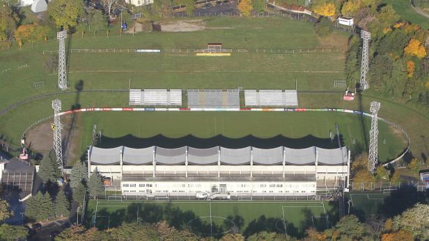 Luftaufnahme eines Fußballstadions mit Tribünen und Flutlichtmasten.