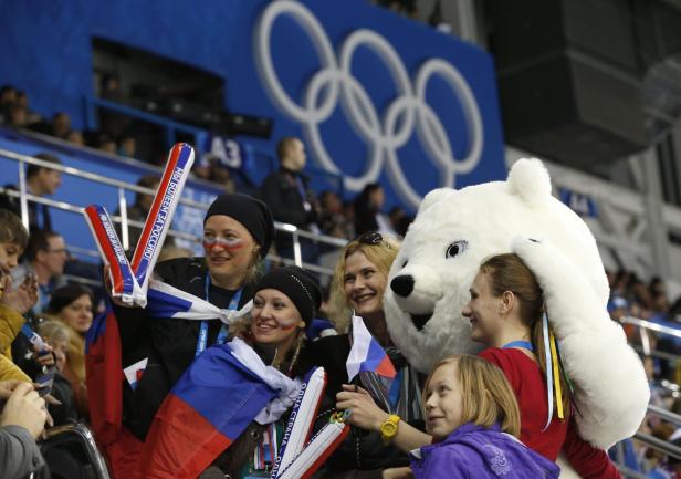 Russische Fans posieren mit einem Eisbären-Maskottchen bei den Olympischen Spielen.