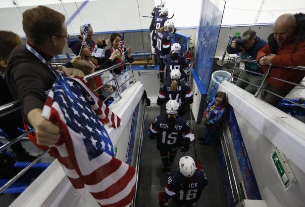 Das US-amerikanische Fraueneishockeyteam betritt das Eis, angefeuert von Fans mit US-Flaggen.