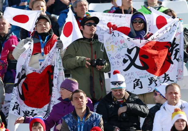 Zuschauer mit japanischen Flaggen und Bannern bei einer Sportveranstaltung.