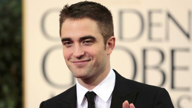 Robert Pattinson lächelt auf dem roten Teppich.
