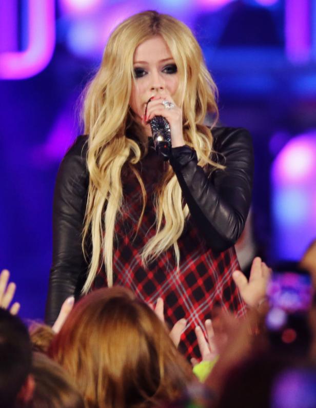 Avril Lavigne singt mit einem Mikrofon in der Hand vor einem Publikum.