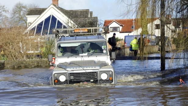 Ein Land Rover fährt durch eine überflutete Straße.