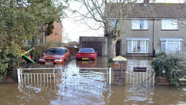 Überschwemmung vor Wohnhäusern, wo das Wasser bis zu den Autos reicht.