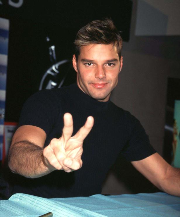 Ricky Martin zeigt mit der Hand ein Friedenszeichen.