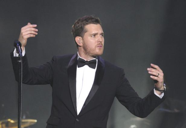 Michael Bublé tritt in einem schwarzen Smoking vor einem Mikrofon auf.
