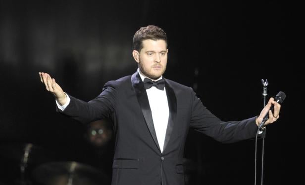 Michael Bublé steht mit ausgebreiteten Armen auf einer Bühne.