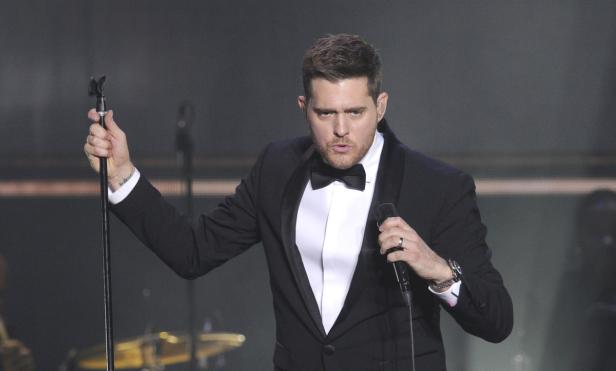 Michael Bublé tritt in einem schwarzen Smoking mit Fliege auf einer Bühne auf.