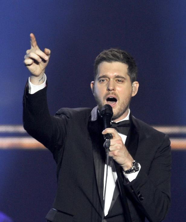 Michael Bublé singt in einem schwarzen Smoking und zeigt mit dem Finger nach oben.
