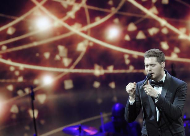 Michael Bublé singt auf einer Bühne mit abstrakten Lichteffekten im Hintergrund.