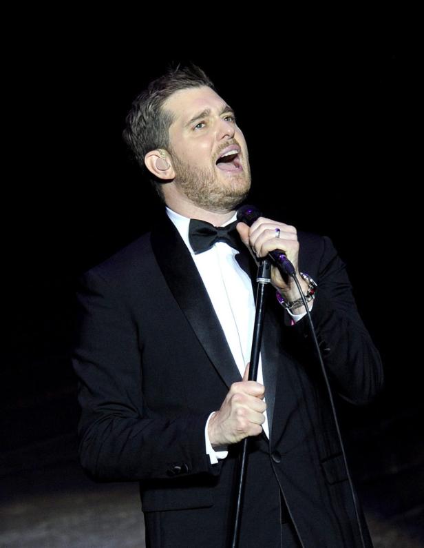 Michael Bublé singt in einem schwarzen Smoking mit Fliege in ein Mikrofon.