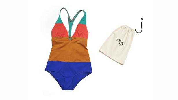 Ein farbenfroher Badeanzug von Hermès liegt neben einem passenden Stoffbeutel.