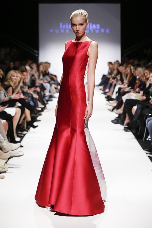 Eine Frau präsentiert ein rotes Abendkleid auf einem Laufsteg.