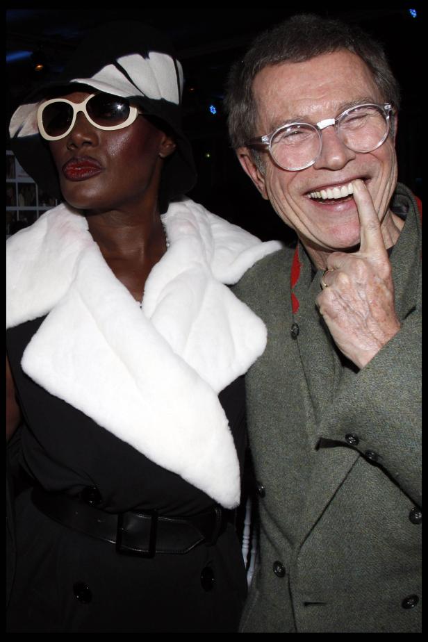Grace Jones mit Hut und Sonnenbrille posiert neben einem lächelnden Mann.